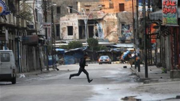 رجل يفر للاحتماء وسط حي باب التبانة بمدينة طرابلس اللبنانية
