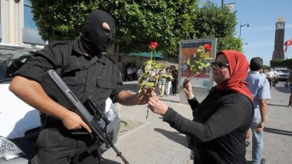 تونسية تقدم ورودا لشرطي في جادة الحبيب بورقيبة خلال تظاهرة لناشطين في المعارضة
