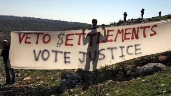 متظاهرون فلسطينيون يحملون لافتة تدعو الى مقاطعة المستوطنات في بلعين بالضفة الغربية 