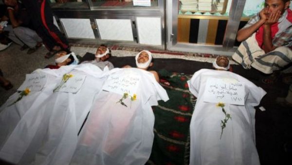 شاب يمني يجلس بجانب جثث متظاهرين قتلوا في ساحة التغيير في صنعاء الخميس