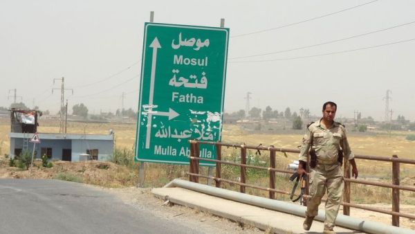 An Iraqi solider walks past a sign pointing toward Mosul. (AFP/File)