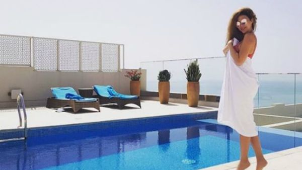 Myriam posted a picture of herself wearing a swimsuit but covering her body with a white towel near the pool (Source: myriamfares - Instagram)