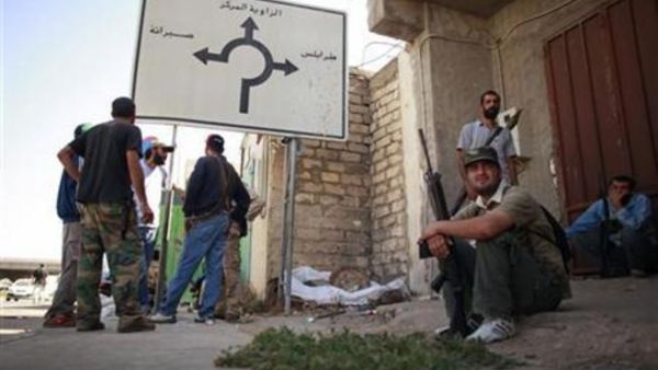 معارضون مسلحون يقفون بالقرب من لوحة ارشادية في وسط مدينة الزاوية
