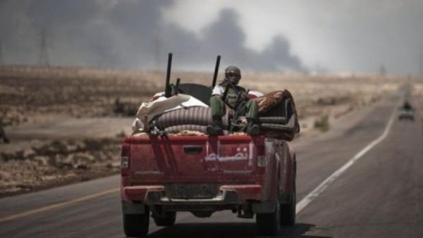 دخان اسود ينبعث من مصنع البريقة للبتروكيماويات فيما تنطلق آلية للمتمرمدين باتجاه خط الجبهة قرب البريقة
