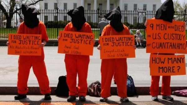 Black hooded human rights activists hold banners demanding the closing of Guantanamo during a protest, part of the Nationwide for Guantanamo Day of Action, outside the White House in Washington DC in April. Photo courtesy of The Week