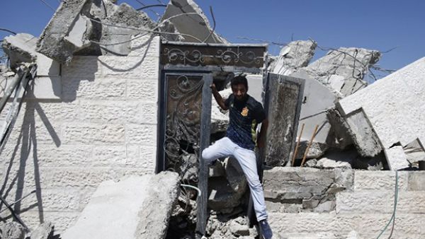 A Palestinian man exists through the door of a house, that was demolished by Israeli army bulldozers, in the village of Qalandia, next to Israel's controversial separation barrier, between the Israeli occupied West Bank town of Ramallah. (AFP/File)