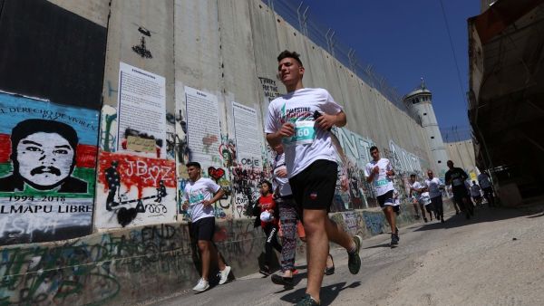  Participants in the Palestine Marathon running along the Israeli apartheid wall surrounding the biblical city of Bethlehem. (Photo: WAFA Images / Ahmad Mizher)