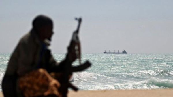A pirate sits on the shore of a Nigerian beach, watching a ship. (AFP/Mohamed Dahir)