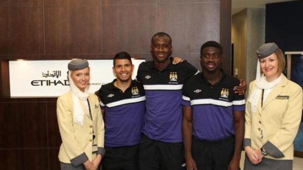 Manchester City Football Club team members Sergio Aquero, Yaya Toure and Kolo Toure flanked by Etihad Airways Business Class Lounge attendants at Manchester Airport before boarding their flight to Beijing