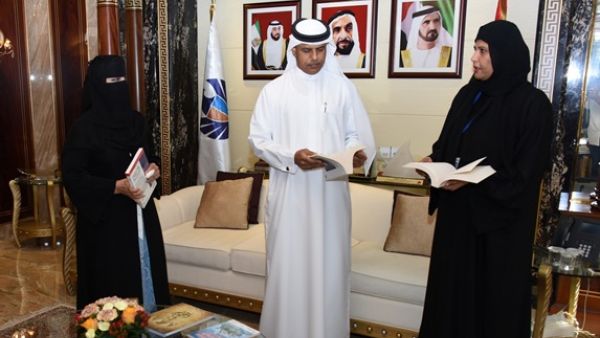 Ahmed Mahboob leafs through one of the books that will be distributed during the campaign, assisted by Sheikha al-Ghaferi and Sheikha Masoud