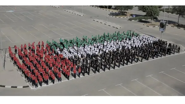 شارك أكثر من 600 طالب من مدرستي كويلا وجي اس اس الدولية تتراوح أعمارهم ما بين السابعة ولغاية الحادية عشر في تشكيل علم بشري بألوان زاهية.