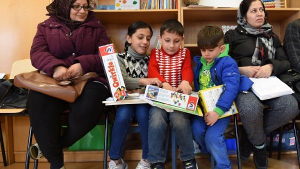 Refugee children and their parents from Afghanistan look at books and games in the refugee camp "Bayernkaserne" in Munich, southern Germany, on March 21, 2016. (AFP/Christof Stache)