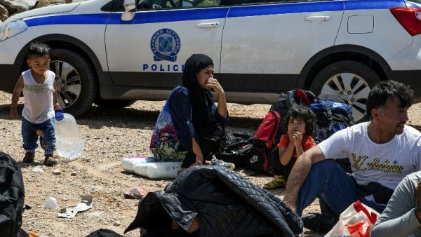 Refugees and migrants wait by a police car in Crete, after being rescued from another capsized vessel on May 31. (AFP/Stringer)