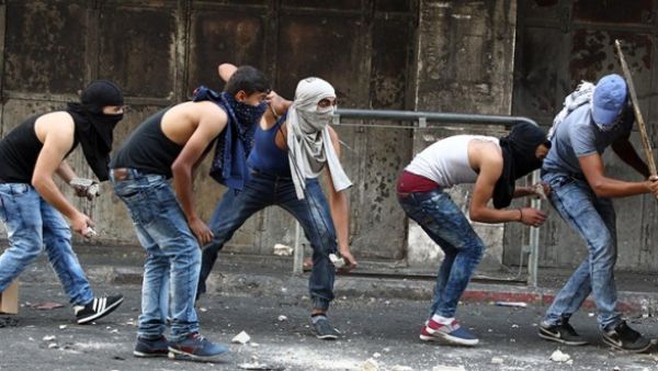 Palestinian youths throw stones towards Israeli security forces during clashes in the West Bank town of Hebron on October 4, 2015. (AFP/File)