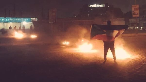 شاب سوداني يرفع علم بلاده خلال التظاهرات ضد الأوضاع الاقتصادية