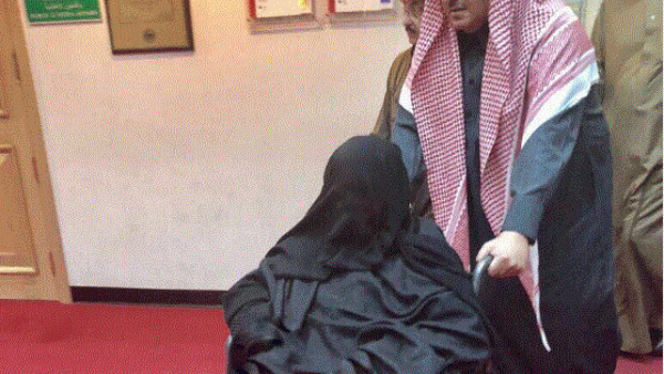 ابن نايف يدفع كرسيا متحركا تجلس عليه والدته، وذلك أثناء خروجهما من المشفى