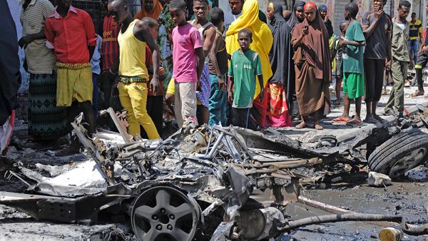 Bystanders look at the wreckage of a car bomb attack in Mogadishu on April 21, 2015. (AFP/Mohamed Abdiwahab)