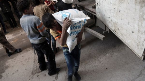 A Syrian child carries a sack of wheat, provided by the World Food Programme (WFP), in Kafr Batna, in the Eastern Ghouta area, on the outskirts of the capital Damascus on March 1, 2016. (AFP/Amer Almohibany)