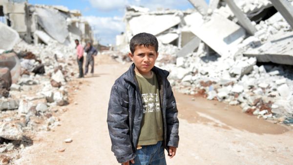 A young Syrian boy poses for a picture between destroyed houses in the northern Syrian town. (AFP/File)