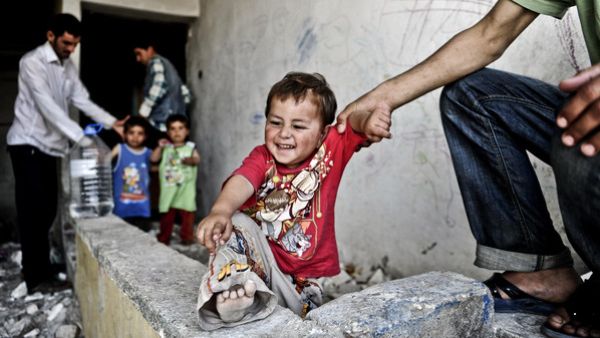 A Syrian man holds his infant in front of a disused house on June 28, 2014 in the Fikirtepe area of Istanbul. (AFP/File)