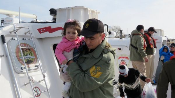 A Turkish Coast guard member holds a child on boat near the village of Kucukkuyu, in western Turkey, on March 8, 2016 after the coast guard arrested a group of migrants and refugees trying to reach the Greek island of Lesbos. (AFP/Stringer)