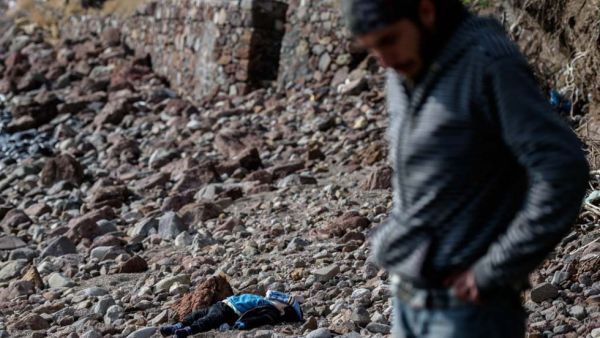 A man stands next to the body of a migrant child washed up on a Turkish beach on January 30, 2016 (AFP/Ozan Kose)