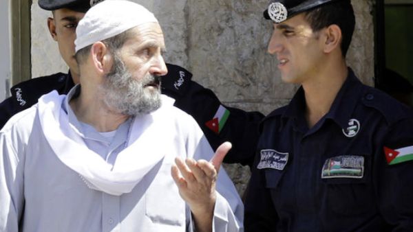 Omar Othman, the father of radical Islamist cleric Abu Qatada, speaks with Jordanian policemen outside the state security court in Amman on July 7, 2013 (Source: AFP/KHALIL MAZRAAWI)