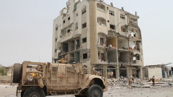 Yemeni fighters loyal to exiled President Abedrabbo Mansour Hadi stand in front of a damaged building in Aden's Khormaksar district on July 15, 2015. (AFP/Saleh al-Obeidi)