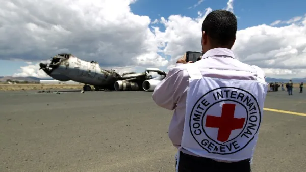 An ICRC worker photographs the wreckage of a Yemeni air force military transport aircraft destroyed by Saudi-led airstrikes. (AFP/Mohammed Huwais)