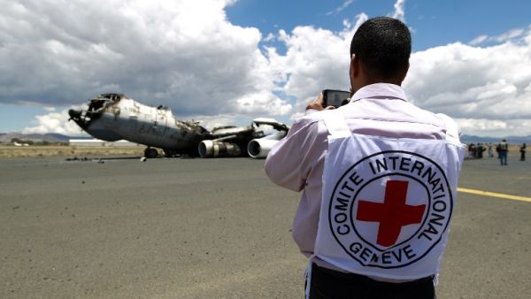 An ICRC worker photographs the wreckage of a Yemeni air force military transport aircraft destroyed by Saudi-led airstrikes. (AFP/Mohammed Huwais)