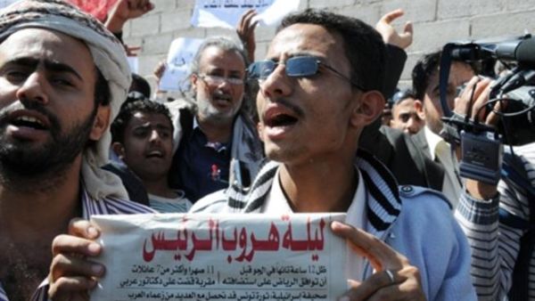 متظاهر يمني يرفع صحيفة غطت حدث هروب الرئيس التونسي/أ.ف.ب