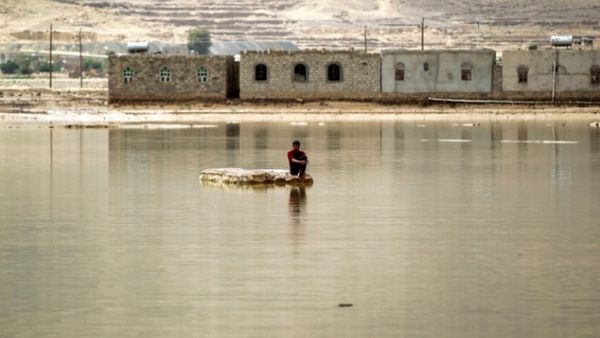 A man sits on a rock in a flooded street following heavy rain in the city of Amran, 50 kms north of Yemen's capital Sanaa on April 15, 2016. (AFP/Mohammed Huwais)