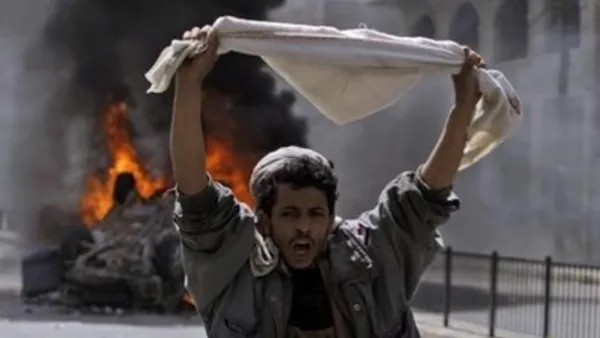 متظاهر يقف امام مركبة محترقة في صنعاء