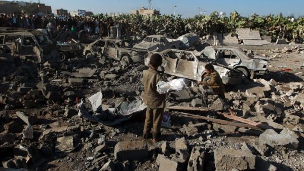 Yemeni civilians stand at the site of a Saudi air strike against Huthi rebels near Sanaa Airport. (AFP/ File)