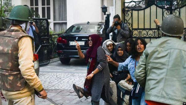 لقطة من الفيديو تظهر عائشة وهي تقارع رجال الشرطة بينما تحمي الشاب من هراواتهم