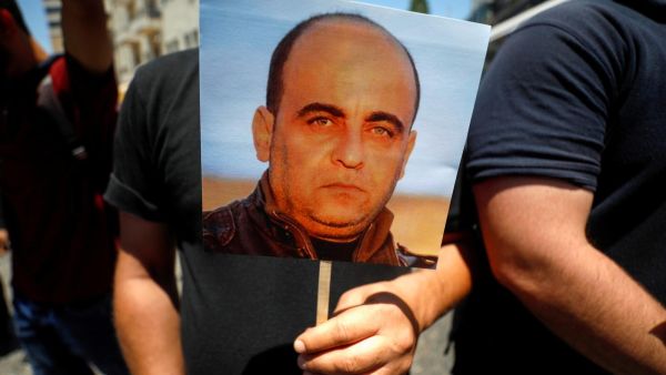 متظاهر يحمل صورة نزار بنات خلال احتجاج في رام الله