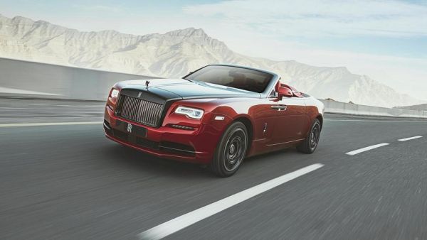 كانت السيارة الحمراء المكشوفة بخطوطها الكلاسيكية في تناقض حاد مع المناظر الطبيعية الصخرية 