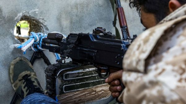A fighter aims a machine gun through a murder hole at a position held by forces loyal to Libya's Government of National Accord (GNA) in the suburb of Wadi Rabie (AFP)