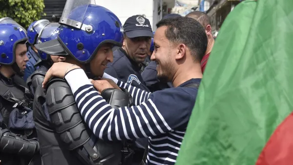 An Algerian man, embraces a member of the security forces during an anti government demonstration in the capital Algiers on April 23, 2019.  RYAD KRAMDI / AFP