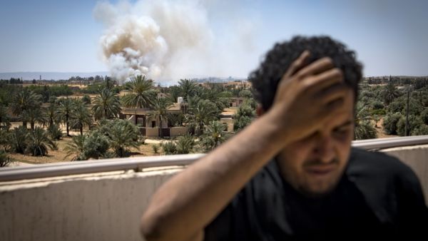 A fighter loyal to the internationally-recognised Government of National Accord (GNA) stands on a rooftop as smoke rises in the distance during clashes with forces loyal to strongman Khalifa Haftar (AFP)