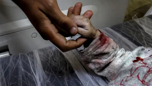 A man holds the hand of Maria al-Gazali, a Palestinian baby, as her body lies on a stretcher at a hospital in Beit Lahia, in northern Gaza Strip  (AFP)