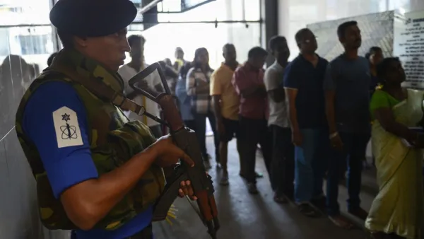 A Sri Lankan Navy personnel stands guard as Catholic devotees pray at St. Anthony's church after it was partially opened for the first time since the Easter Sunday attacks in Colombo (AFP)