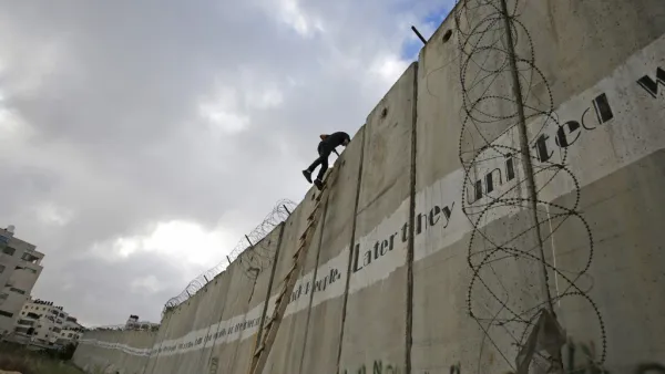 Palestinian youths climb a section of Israel's separation wall to reach at the al-Aqsa Mosque compound in Jerusalem (AFP)