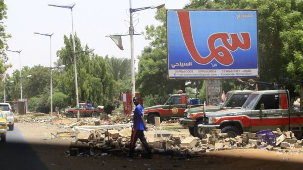 A man crosses a street as vehicles belonging to members of Sudan's paramilitary Rapid Support Forces are lined up in Khartoum's Nile street in the capital   (AFP)