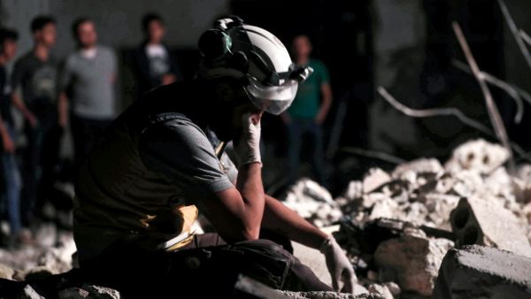 A member of the Syrian Civil Defence, also known as the "White Helmets", reacts as his comrades clear debris while searching for bodies or survivors in a collapsed building following a reported government air strike in the village of Saraqib in Syria's northwestern Idlib province  (AFP)
