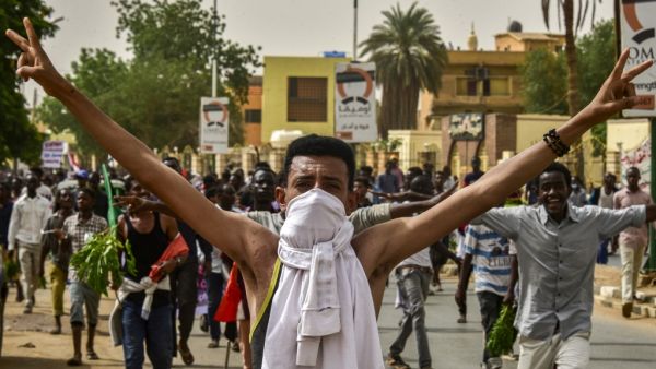 A Sudanese protester covering his face with a jersey flashes the victory gesture while marching with others in a mass demonstration against the country's ruling generals in the capital Khartoum's twin city of Omdurman on June 30, 2019.  Ahmed MUSTAFA / AFP