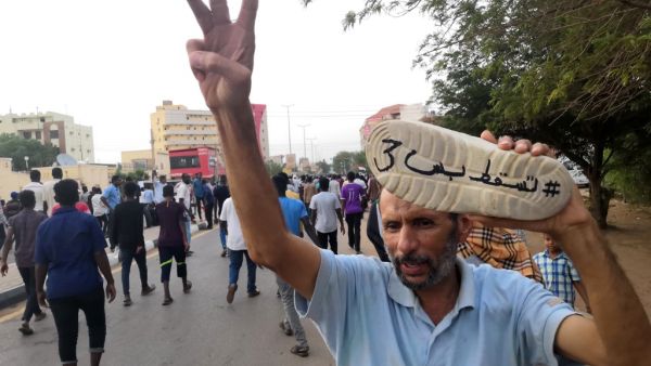 A Sudanese protester flashes the gesture for the number three as he raises a shoe painted with the Arabic words "#JustFall3" during a mass demonstration against the country's ruling generals in the capital Khartoum on June 30, 2019.  AFP