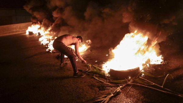 متظاهر لبناني مناهض للحكومة يحرق إطارات لسد الطريق السريع الساحلي شمال العاصمة بيروت