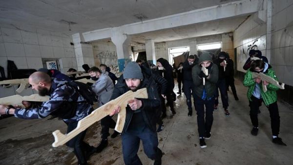 A military instructor teaches civilians holding wooden replicas of Kalashnikov rifles, as they take part in a training session at an abandoned factory in the Ukrainian capital of Kyiv on February 6, 2022. (Photo by Sergei SUPINSKY / AFP) Ukraine’s International Invitation to Foreign Fighters