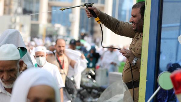 A Saudi policeman spays Muslim pilgrims with water to cool them off near the Grand Mosque (Karim Sahib/AFP)